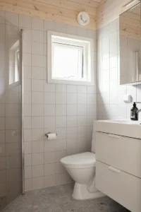 Badrum med vitt kakel, gråa klinkers i ett kompakt boende