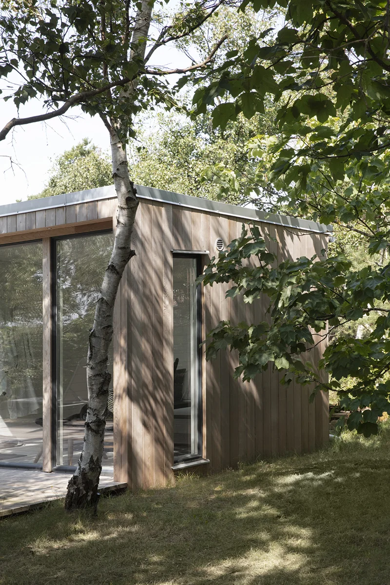 Bastuhus med relax exteriör i trä med ett träd framför