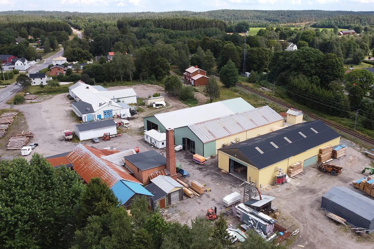 Bild på snickeriet sett snett från ovan, består av tre lokaler omgivna av skog och andra fabriker.
