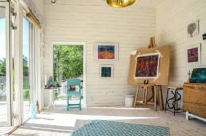 Attefallshus med atelje inrett med stafli, sitthörna och vit träpanel med tavlor på