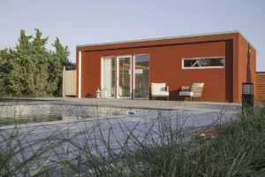 Rött bastuhus med fyra fönster, en stor altan och pool framför