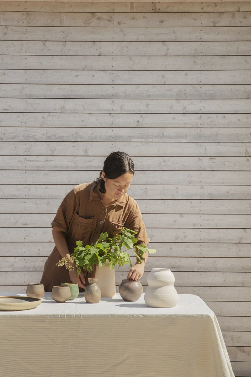 Emma utanför sitt attefallshus ställer upp sina keramikalster på ett bord