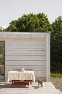 Attefallshus i trä med matgrupp på en altan framför