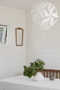 Detalj i attefallshus med vita träväggar över bordshörna med kruka på