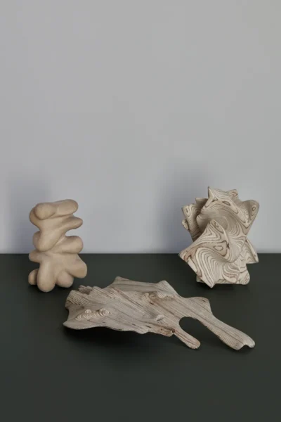 Träskulpturer på en grön skiva mot vit vägg