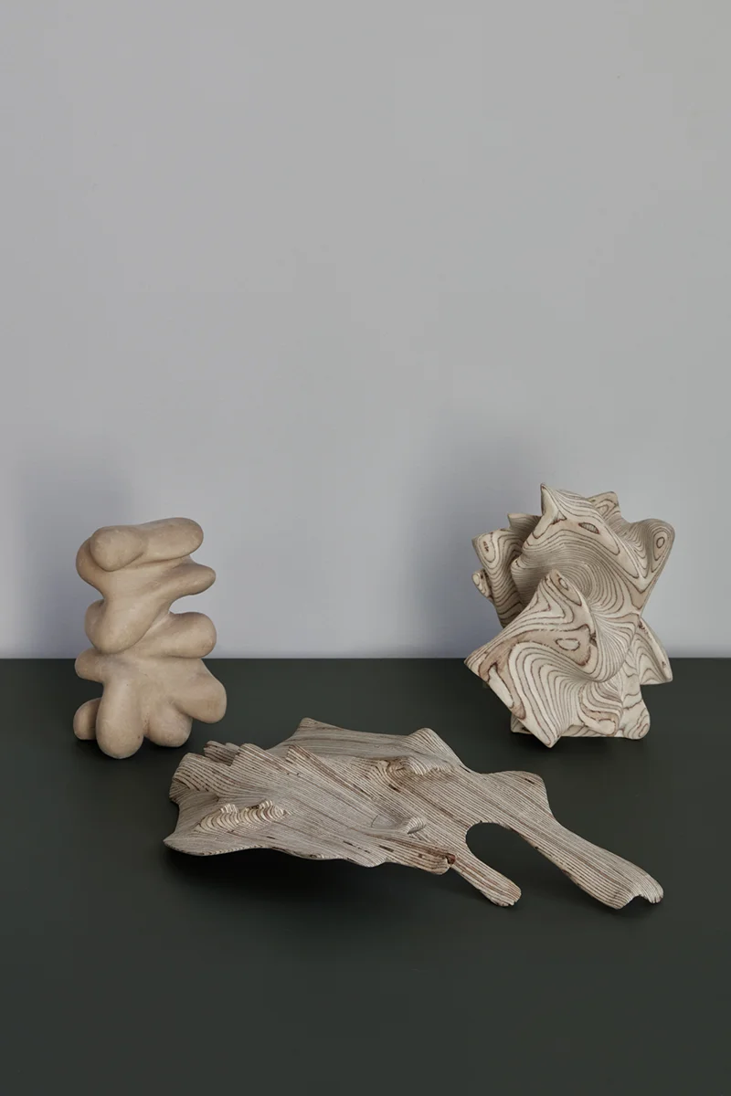 Träskulpturer på en grön skiva mot vit vägg