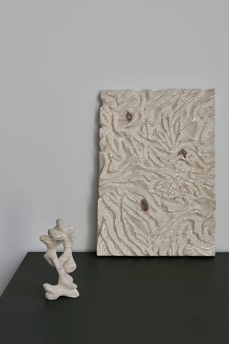 Träskulpturer på en grön skiva mot vit vägg