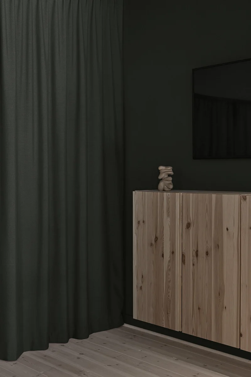 Träskåp med skulptur på bredvid en grön gardin mot grön vägg