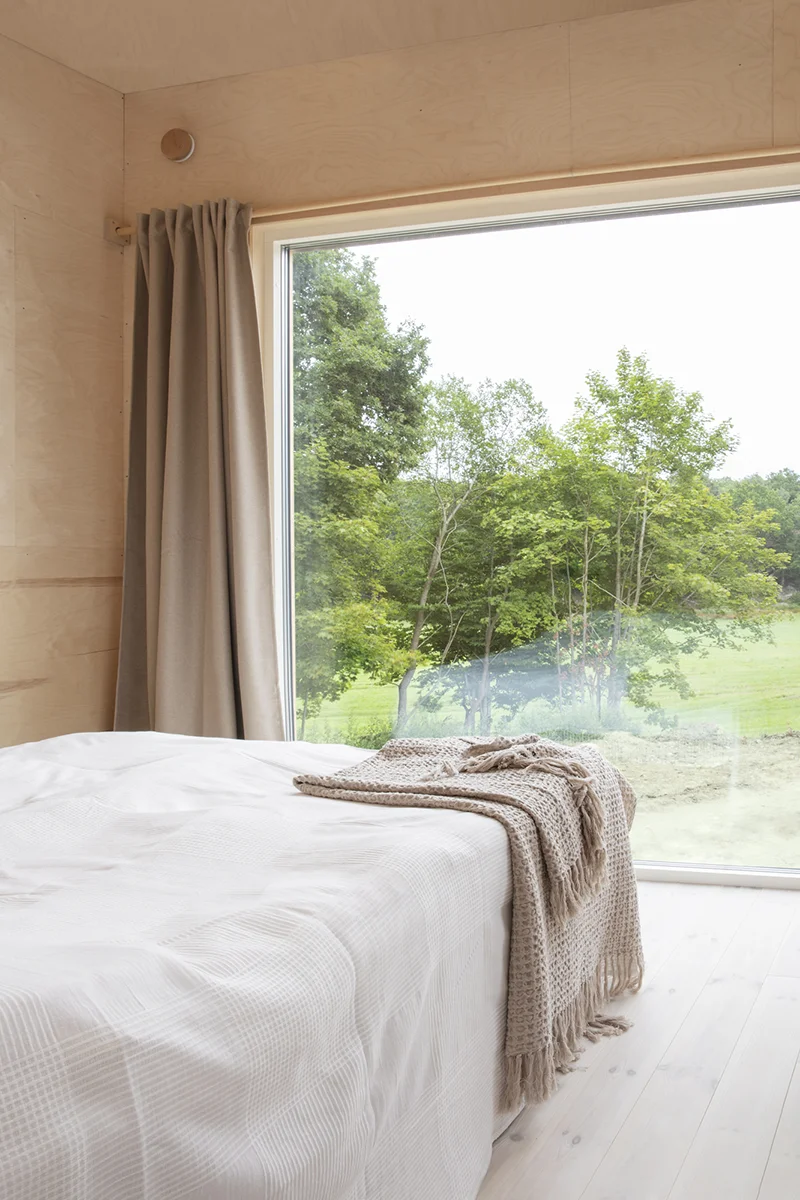 Sovrum med stort fönster med utsikt över äng