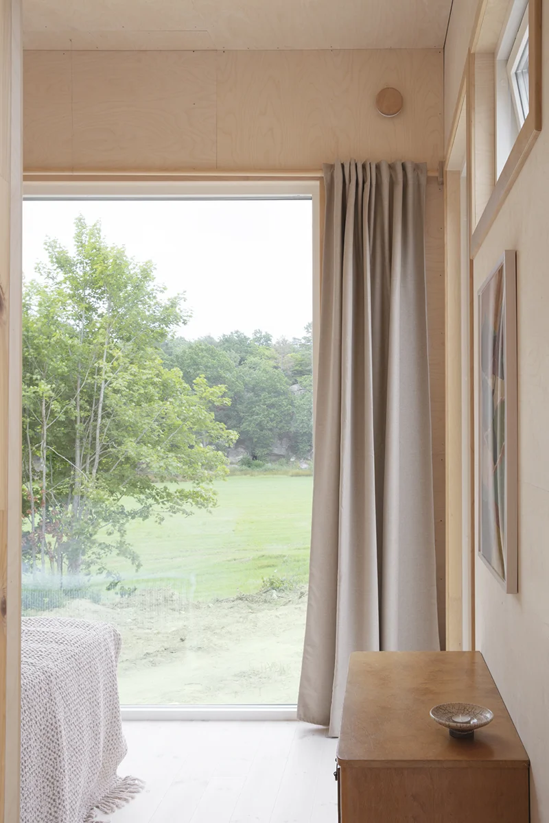 Sovrum med stort fönster med utsikt över äng