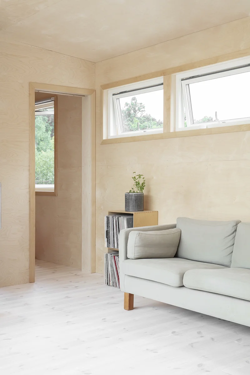 Vardagsrum med plywoodväggar, soffa bredvid LP-hylla