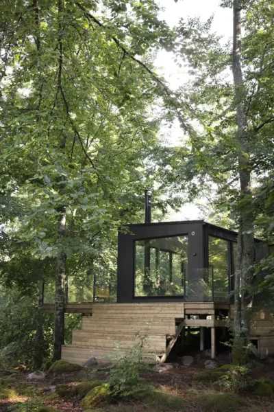 Svart modulhus med stora fönster i en skog