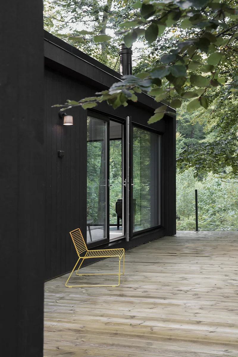 Svart modulhus med stora fönster i en skog