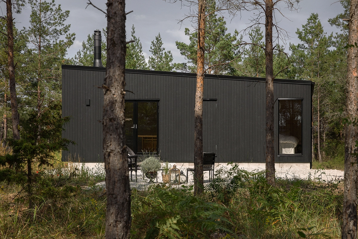 panorama modernt svart hus fran enkelrum i skogen pa gotland