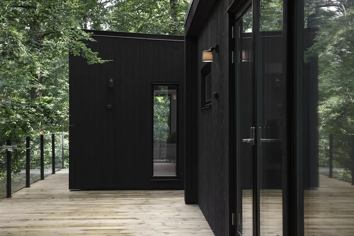 A house at an angle, with black wooden panels and large windows