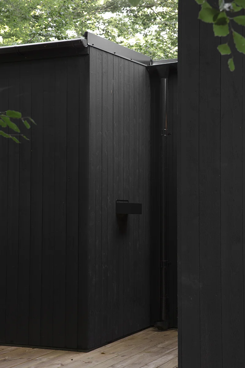 House with black wooden panel surrounded by green leaves
