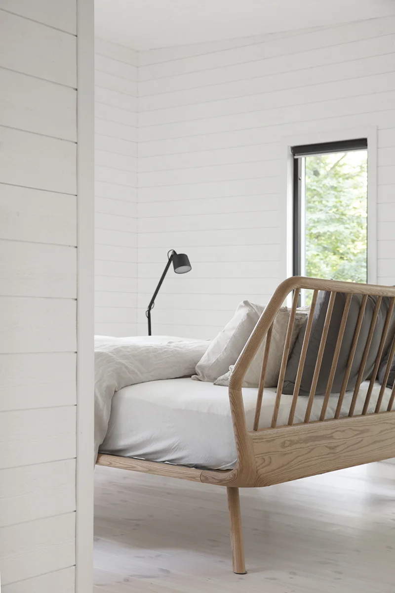 Bed in a bedroom with white-painted wooden panels