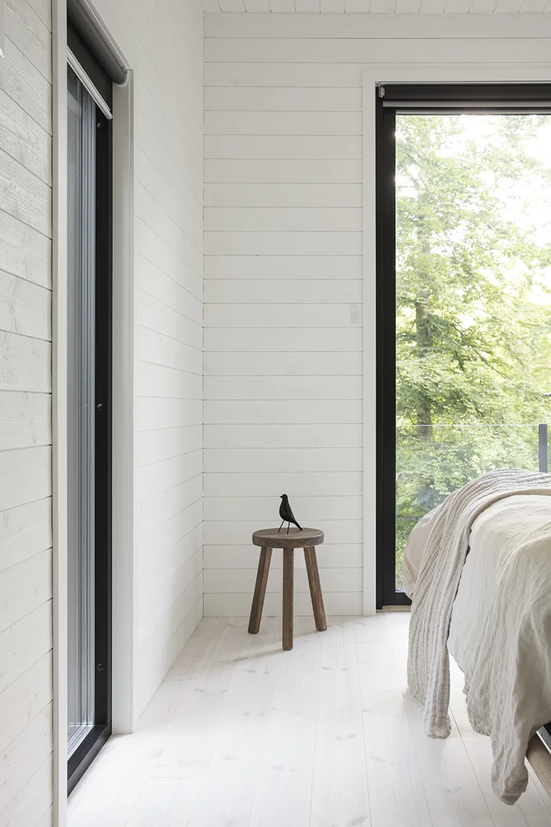 White-painted wooden panels in a bedroom, with a stool in the corner next to a large window