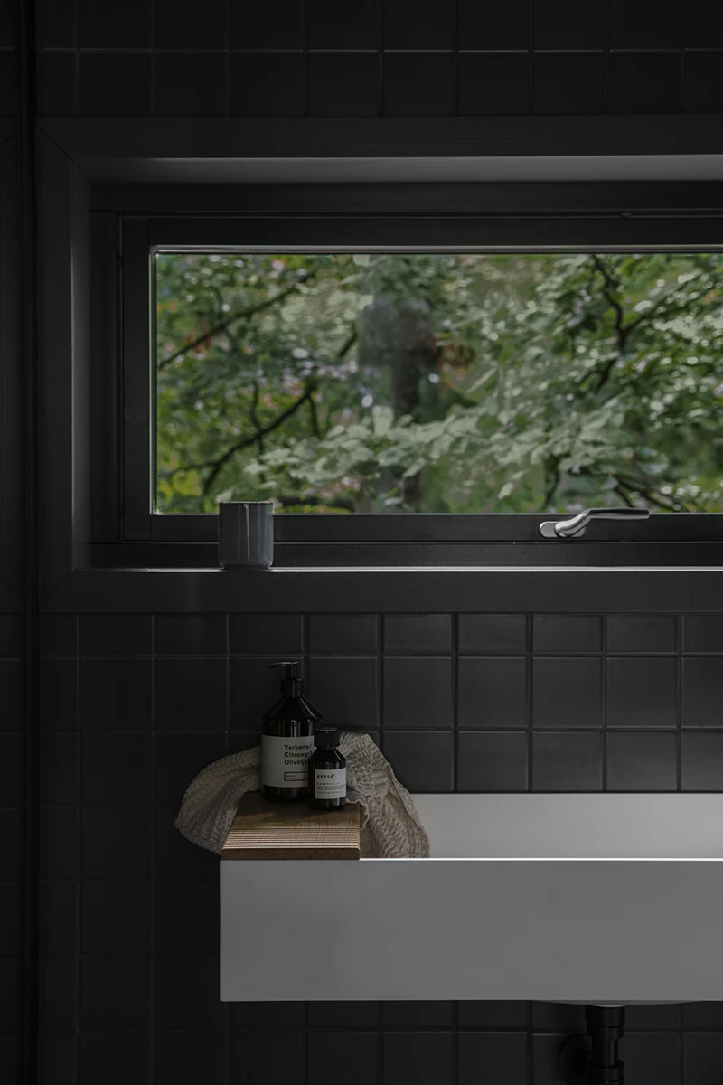 Grey tiled bathroom with white sink under a window